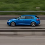 Schnell fahrendes Auto in der Seitenansicht auf einer Straße mit Leitplanke