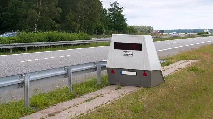 Graue Messsäule am Rand einer Autobahn hinter der Leitplanke - in solchen Gehäusen werden Laserscanner wie der PoliScan FM1 betrieben