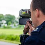 Polizeibeamter visiert mit einem Laserhandmessgerät ein Fahrzeug an